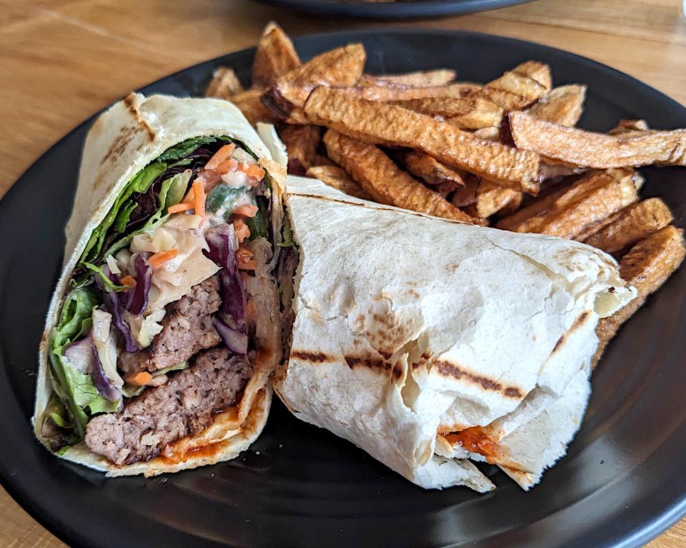 A wrap featuring Impossible burger, a peanut butter sauce, and veggies.